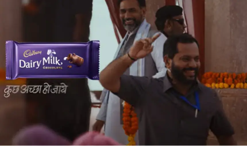 Dairy Milk ad with chocolate packaging and happy crowd.