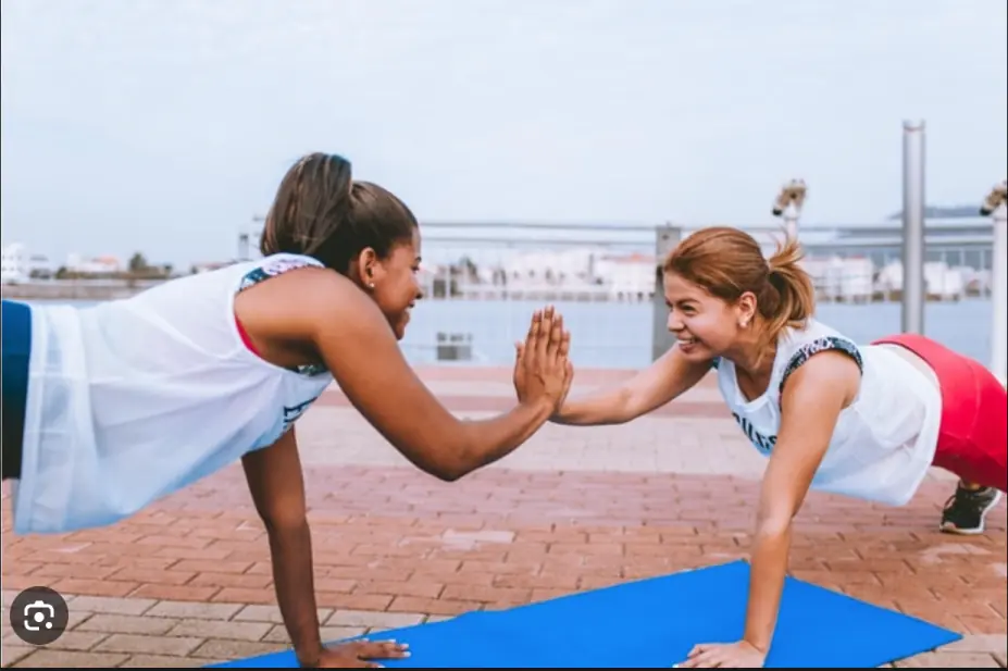 Two women high-fiving during a waterfront workout session, representing active lifestyle photography.