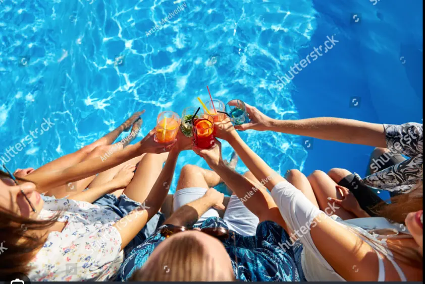 Friends relaxing by the pool with drinks in hand, symbolizing a fun lifestyle.